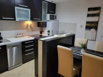 a kitchen with black cabinets and yellow chairs at Luxury Apartment in Mladenovac