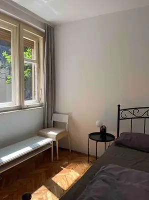 a bedroom with a bed and a chair and a window at Central Home in Belgrade in Belgrade