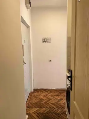 a hallway with a white wall and wooden floors at Central Home in Belgrade in Belgrade