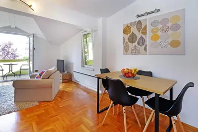 a kitchen and living room with a table and chairs at Red Tree Apartment in Belgrade