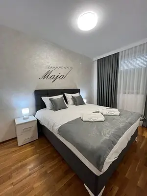 a bedroom with a large bed with a happy anniversary sign on the wall at Apartman Maja in Ruma