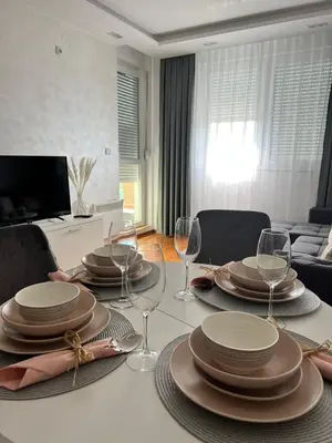 a dining room table with plates and wine glasses at Apartman Maja in Ruma