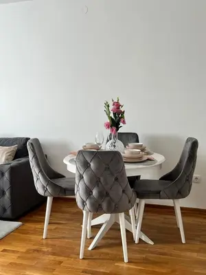 a dining room table and chairs with a vase of flowers at Apartman Maja in Ruma