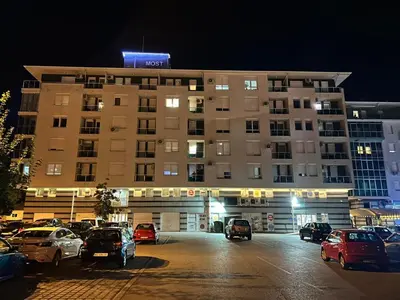 a large building with cars parked in a parking lot at Apartman Maja in Ruma