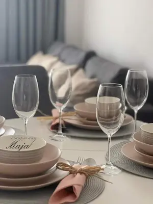 a table with plates and wine glasses on it at Apartman Maja in Ruma