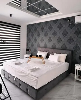 a bedroom with a large bed with a gray wall at Vila Grof in Vinča