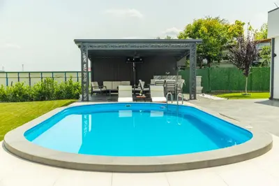 a pool in a backyard with a table and chairs at Vila Grof in Vinča
