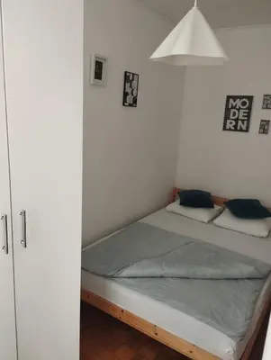 a bedroom with a bed and a white wall at Apartman Vuković in Novi Beograd