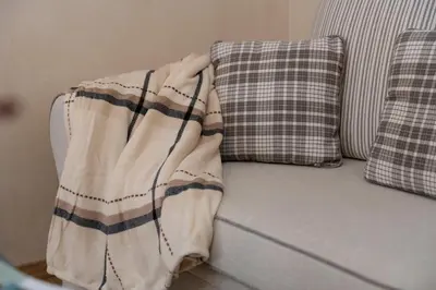 a blanket sitting on a couch with two pillows at 1-bedroom apartment near airport in Surčin