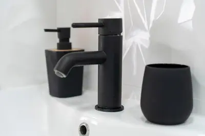 a bathroom with two black faucets on a counter at 1-bedroom apartment near airport in Surčin