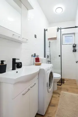 a white bathroom with a washing machine and a sink at 1-bedroom apartment near airport in Surčin