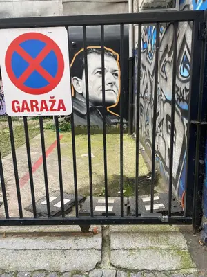 a gate with a sign in front of a mural at Apartment in Belgrade with small parking space in Belgrade