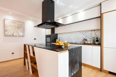 a kitchen with white cabinets and a black counter top at 1-Bedroom Apartment with Balcony in Ledine
