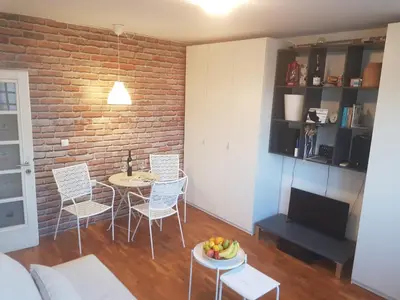 a living room with a table and chairs and a brick wall at Dorcol Rooftop Apartment in Belgrade