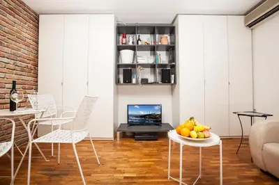 a living room with white furniture and a fireplace at Dorcol Rooftop Apartment in Belgrade