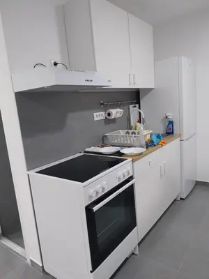 a kitchen with white cabinets and a stove top oven at Garden Apartment New Belgrade in Novi Beograd
