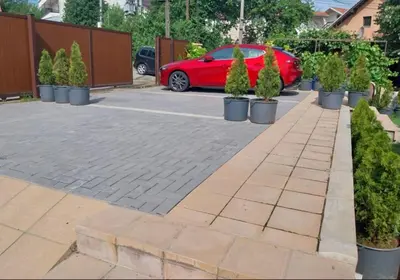 a red car parked in a driveway with potted trees at Garden Apartment New Belgrade in Novi Beograd
