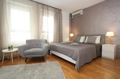 a bedroom with a bed and a chair and a window at Kokpit - Stan Na Dan Novi Beograd Belvil, parking 5 evra dan in Belgrade