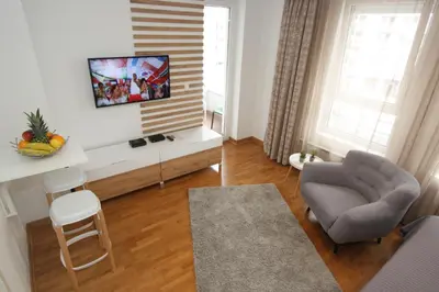 a living room with a chair and a tv on a wall at Kokpit - Stan Na Dan Novi Beograd Belvil, parking 5 evra dan in Belgrade