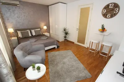 a bedroom with a bed and a chair and a clock at Kokpit - Stan Na Dan Novi Beograd Belvil, parking 5 evra dan in Belgrade
