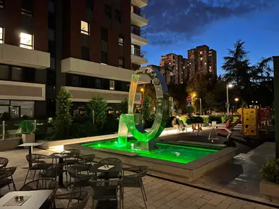 a green fountain in a courtyard with tables and chairs at THE FIVE-New Belgrade Apartment in Belgrade