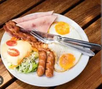 a plate of breakfast food with eggs bacon and sausage at Topli Dom Obrenovac in Obrenovac