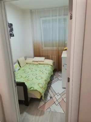 a small bedroom with a bed and a window at Topli Dom Obrenovac in Obrenovac