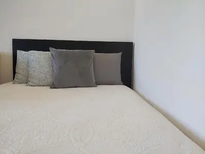 a white bed with a black headboard and pillows at Apartman Elena Dedinje in Belgrade