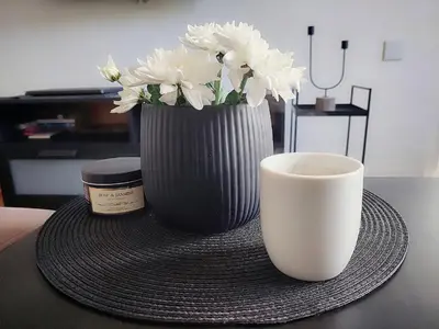 a cup of coffee and a vase of flowers on a table at Apartman Elena Dedinje in Belgrade