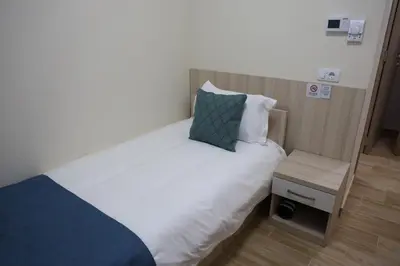 a bedroom with a white bed with a blue pillow at home in superior如家 in Surčin