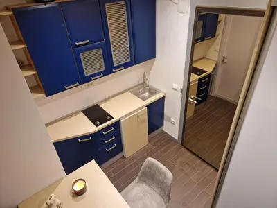 a small kitchen with blue cabinets and a chair at Jacuzzi Vaki Apartment in Belgrade