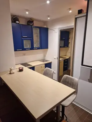 a kitchen with blue cabinets and a table and chairs at Jacuzzi Vaki Apartment in Belgrade