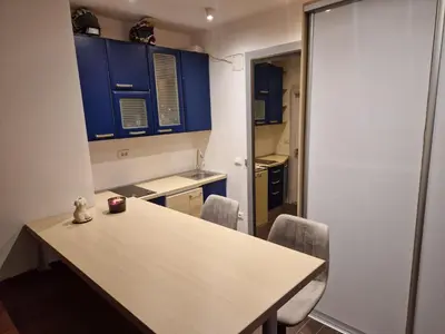a kitchen with blue cabinets and a table and chairs at Jacuzzi Vaki Apartment in Belgrade