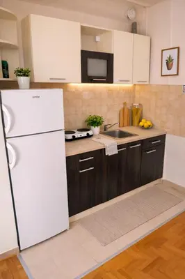 a kitchen with a white refrigerator and wooden cabinets at Apartman Quality in Voždovac