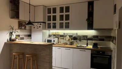 a kitchen with white cabinets and a counter with stools at Sanska 25 in Dušanovac (historical)