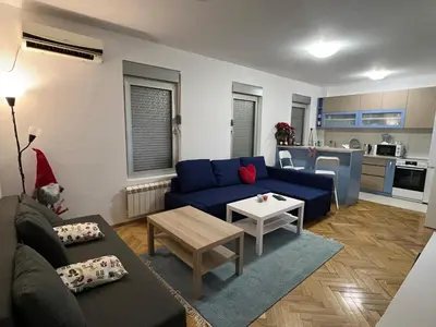 a living room with a blue couch and a kitchen at Lovely flat in Vračar (historical)
