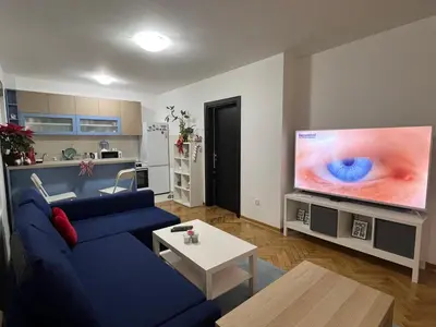 a living room with a blue couch and a large tv at Lovely flat in Vračar (historical)
