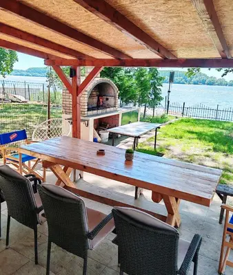 a wooden table and chairs on a patio with an oven at Dadula na Dunavu in Kovin