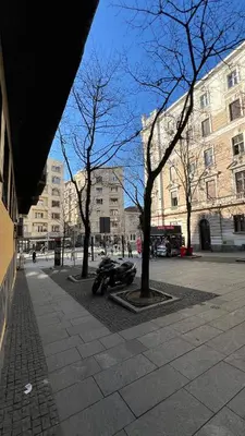 a motorcycle parked next to trees on a city street at Central Sky View Apartment in Belgrade