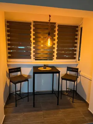 a table and two chairs in a room with windows at Central Sky View Apartment in Belgrade