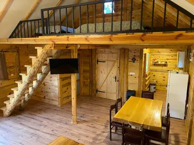 a room with a dining table and a loft at Vikendica Milošević in Arandjelovac