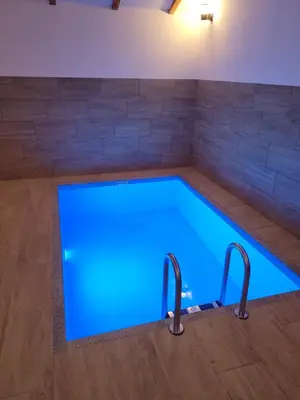 an indoor swimming pool with blue lighting in a room at Vikendica Milošević in Arandjelovac