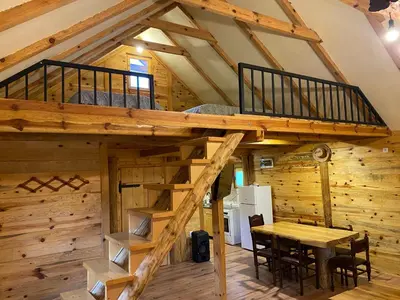 a loft bed in a log cabin with a dining table at Vikendica Milošević in Arandjelovac