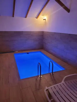 a large swimming pool in a room with a bench at Vikendica Milošević in Arandjelovac