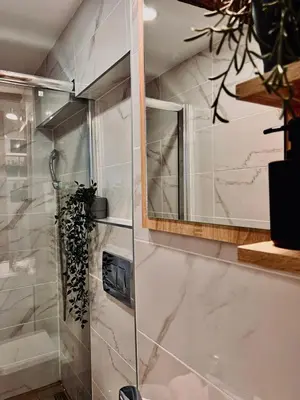 a bathroom with a glass shower with a mirror at Stone House Central Belgrade Studio in Belgrade