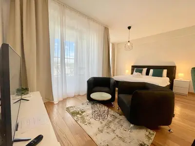 a bedroom with a bed and two chairs and a television at Green - stan na dan studio Novi Beograd, parking 5 evra dan in Belgrade