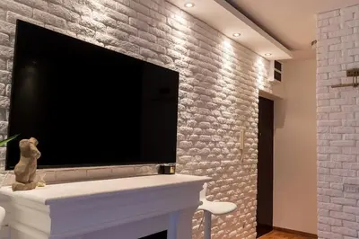 a living room with a large tv on a brick wall at Royalux Zemun Residences in Belgrade