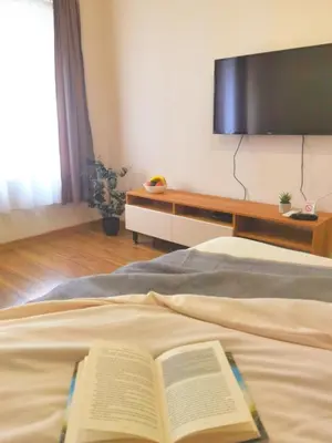a book laying on top of a bed with a tv at Dani Lux Belgrade Center Studio Apartment in Belgrade