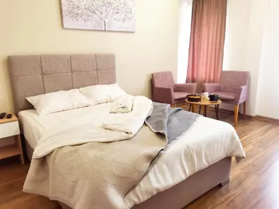 a bedroom with a large bed and two chairs at Dani Lux Belgrade Center Studio Apartment in Belgrade