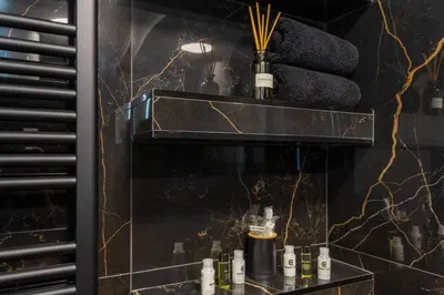 a bathroom with a shelf with bottles of perfume at Royalux Kennedy Residences in Tošin Bunar